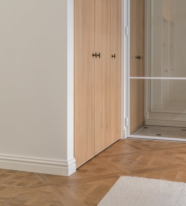 Hall avec un parquet Versailles, une armoire en chêne et des plinthes blanches
