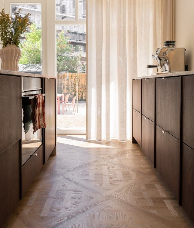 Cuisine avec porte-fenêtre, rideaux en lin et un parquet Versailles au soleil