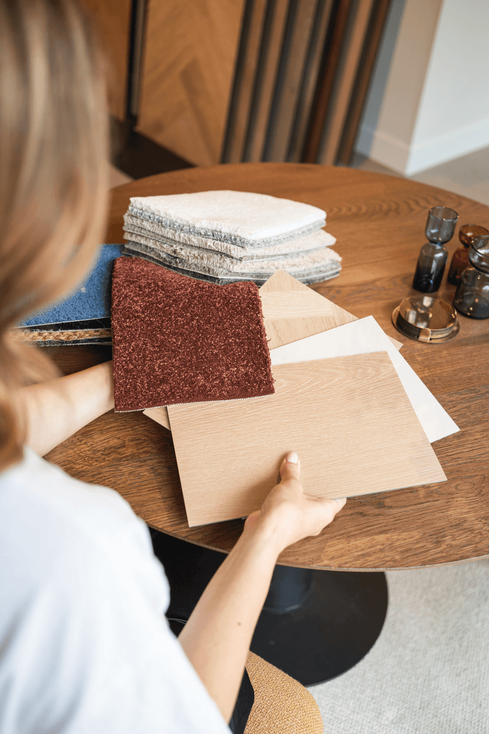Interieurstylist aan de showroomtafel van Solza met vloer- en tapijtstalen in haar handen
